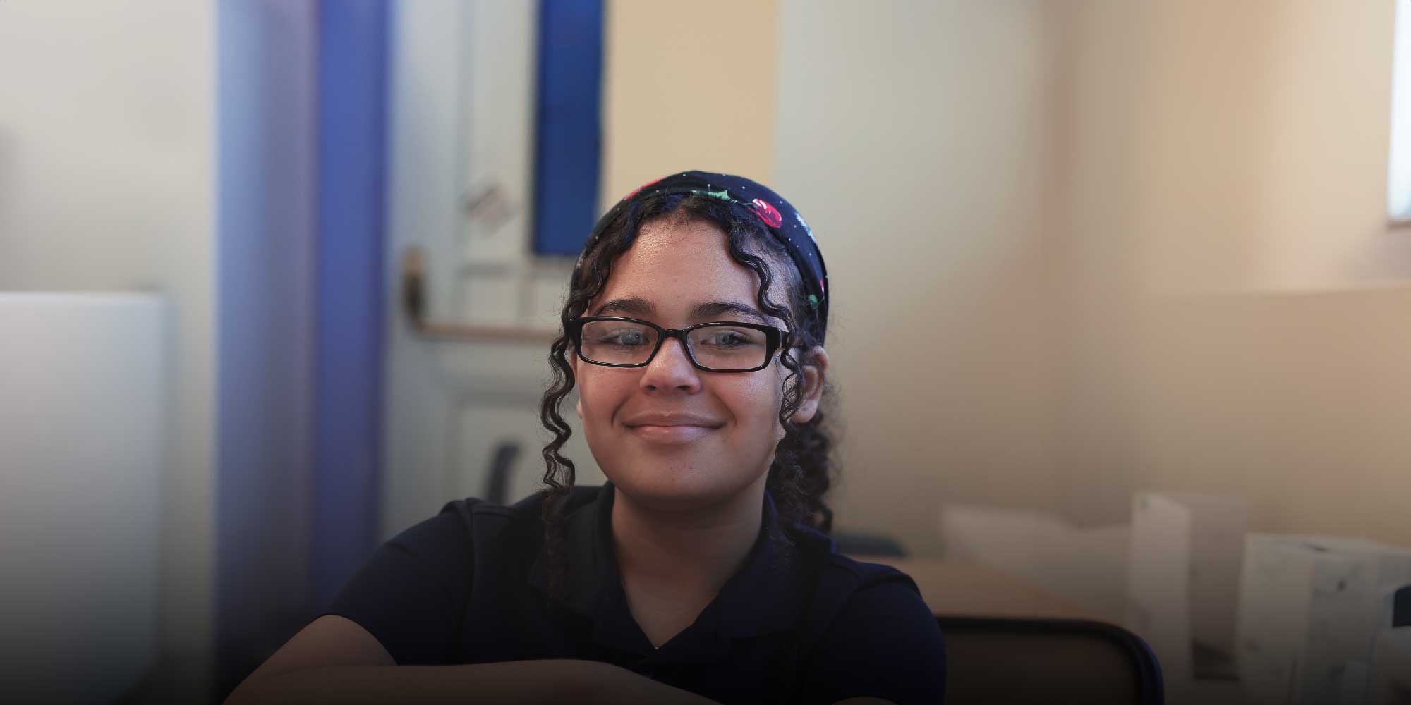 Smiling West Park student with glasses and a patterned headband.